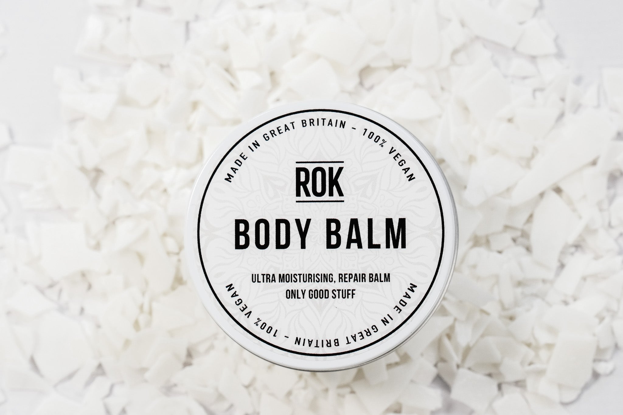 ROK Body Balm tin surrounded by white cocoa butter flakes – vegan ultra moisturising repair body balm UK