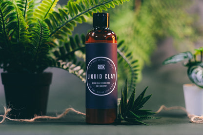 ROK Liquid Clay bottle with tropical plants in background – vegan matte hair texturiser UK
