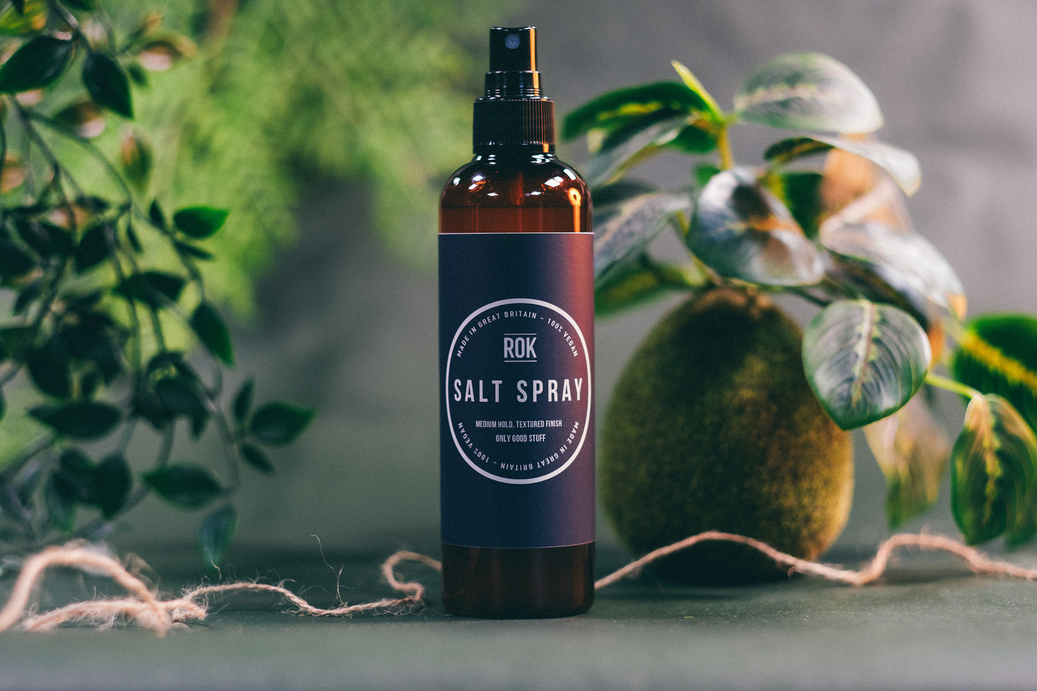 ROK Salt Spray bottle with tropical plant background – medium hold textured finish hair spray