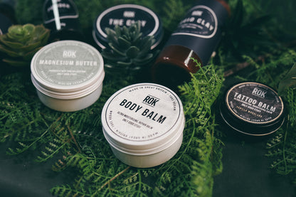 Full ROK Products skincare range on green fern – Body Balm, Magnesium Butter, Tattoo Balm, Liquid Clay and The Clay
