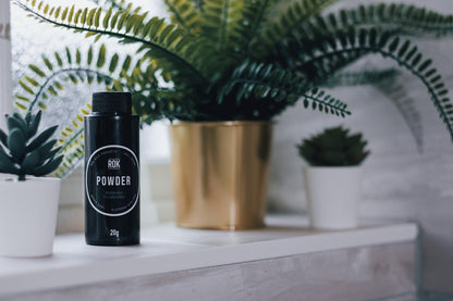 ROK Powder bottle on shelf with fern and succulent plants including gold pot – hair texture powder