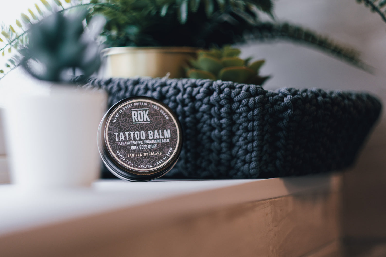 ROK Tattoo Balm tin with woven basket and tropical plant display – vegan tattoo care UK