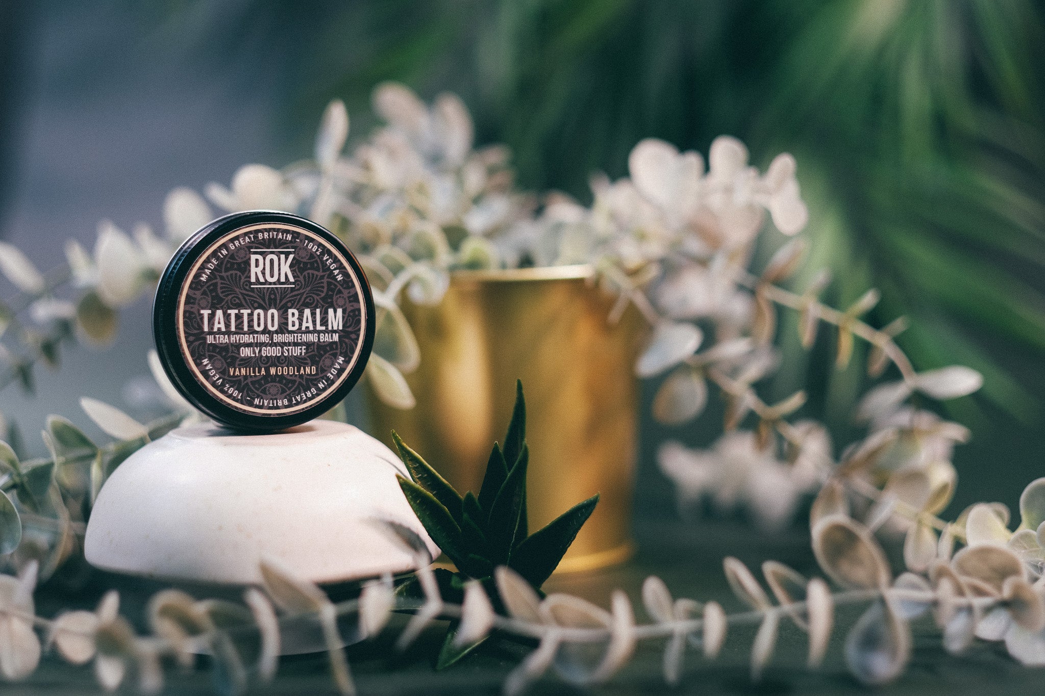 ROK Tattoo Balm tin with gold pot and white botanical flowers – vegan tattoo moisturiser UK
